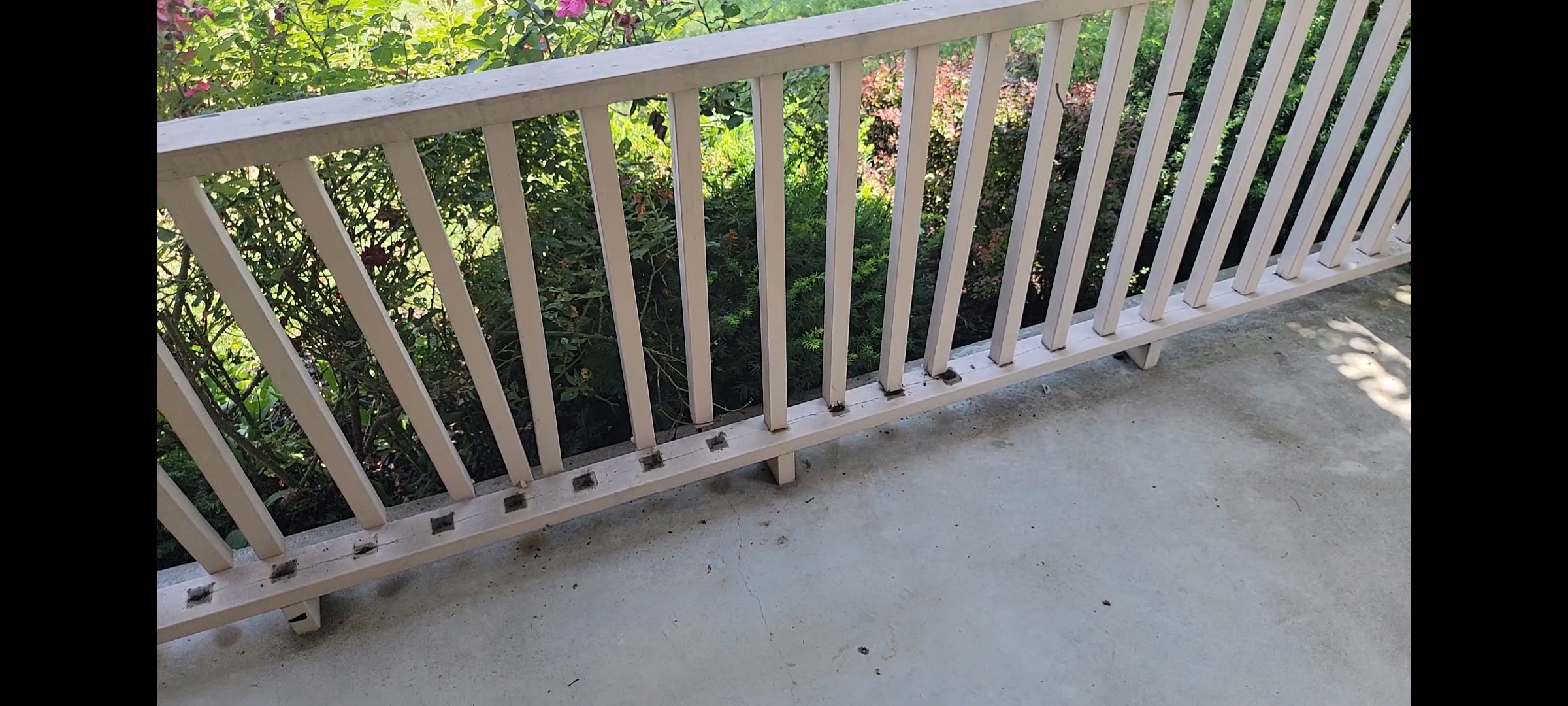 image of wooden porch rail protected by thin residential paint , its rotten and its spindles are falling apart and coming disconnected. It needs better protection
