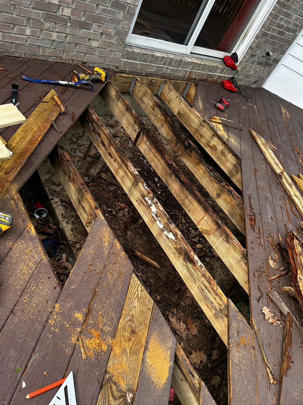 picture shows a deck floor with a section of boards removed and its obvious they were rotten because the joist are exposed and they have rot, the area is big but not huge making up about 7 or 8 deck boards in width and length. The purpose is to shpow there was floor board rot and underneath joist rot to the deck